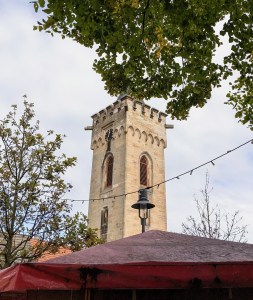 Man sieht ein rotes Zeltdach, darüber hängt eine Lichterkette. Im Hintergrund ragt über das Dach der Udenheimer Glockenturm.