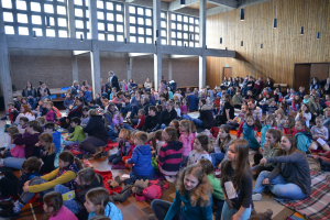 Kinder sitzen auf dem Kirchenboden udn feiern zusammen einen Familiengottesdienst