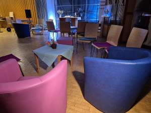 Bunte Sessel und Sofas in kleinen Gruppen vor dem Altar