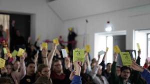 Man sieht wie viele Menschen eine Stimmkarte in die Höhe heben