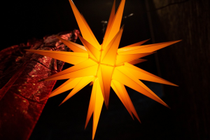 Orange leuchtender Herrnhuter Stern vor schwarzem Abendhimmel