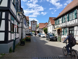 Eine Straße, eingerahmt von Fachwerkhäusern, an deren Ende ein Ortseingangsturm steht.