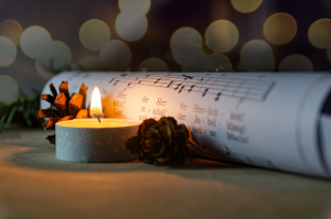 Brennendes Teelicht neben einem gerollten Notenblatt
