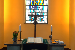 Altar der Stadtkirche mit Kreuz und Bibel, 2 Kerzen und rotem Tulpenstrauß