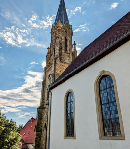 Blick auf die Evangelische Kirche in Stein-Bockenheim. Man sieht den Kirchturm und einen Teil des Kirchenschiffs mit zwei Fenstern.