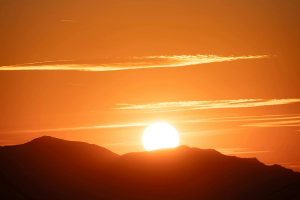Feurige Sonne geht hinter Bergrücken auf