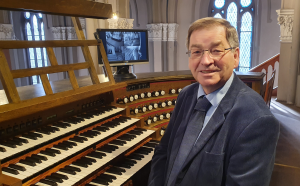 Hans-Uwe Hielscher vor einem großen Orgelmanual auf der Orgelempore