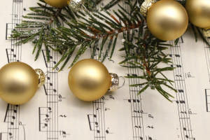 Goldene Weihnachtskugeln und ein Tannenzweig liegen auf einem Notenblatt.