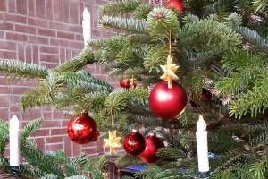 Rote Kugeln, goldene Sterne und weiße Kerzen hängen an den Zweigen des Weihnachtsbaums