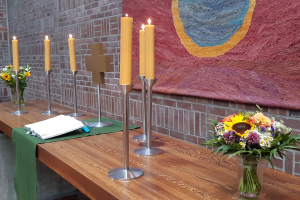 Altar der Johanneskirche, bunter Blumenstrauß, 6 Kerzen, in der Mitte das Kreuz, davor die Bibel