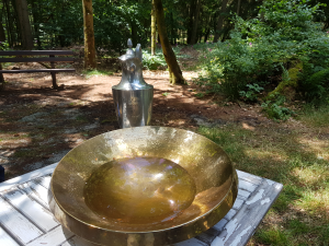 Taufbecken und Kelch auf einem Tisch im Wald